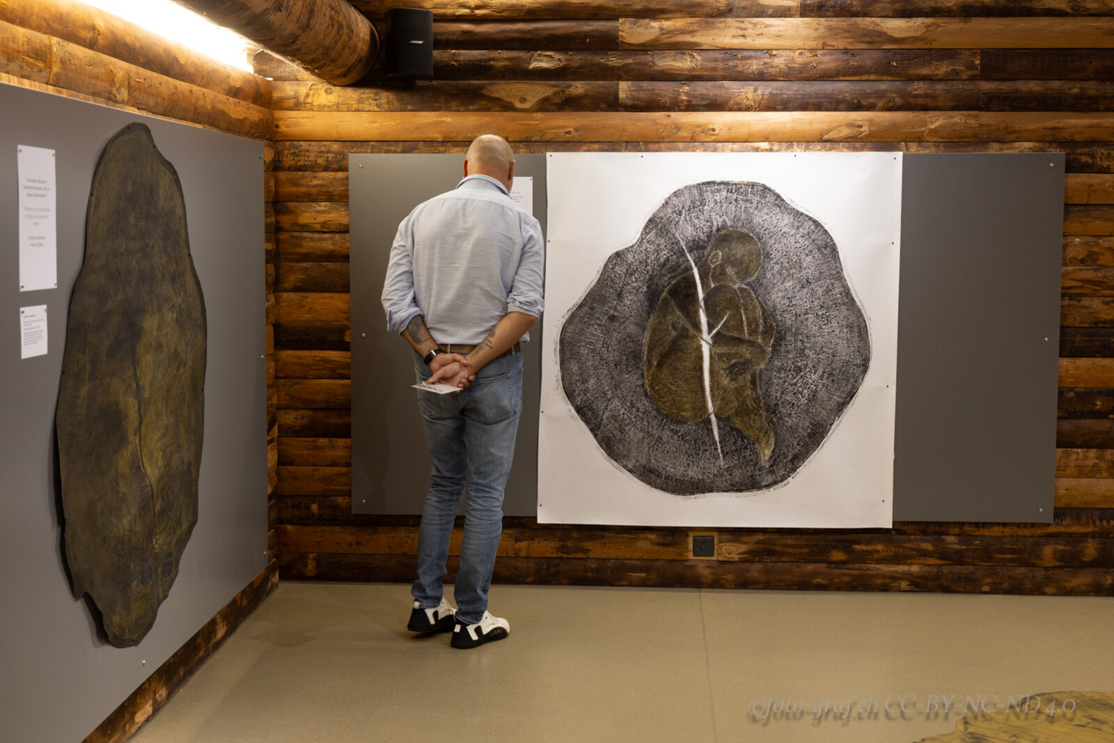 A visitor viewing the tondo print of a figure within tree rings.