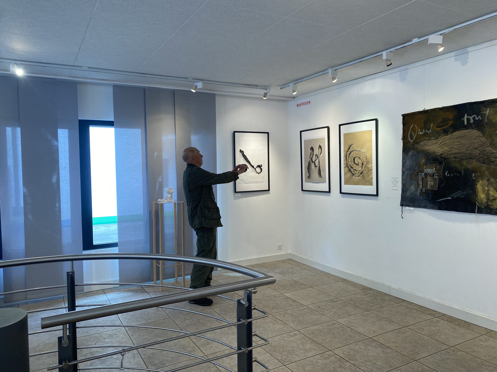 Visitor viewing framed works on paper at the Présence/Absence exhibition, Espace Raiffeisen, Champéry.