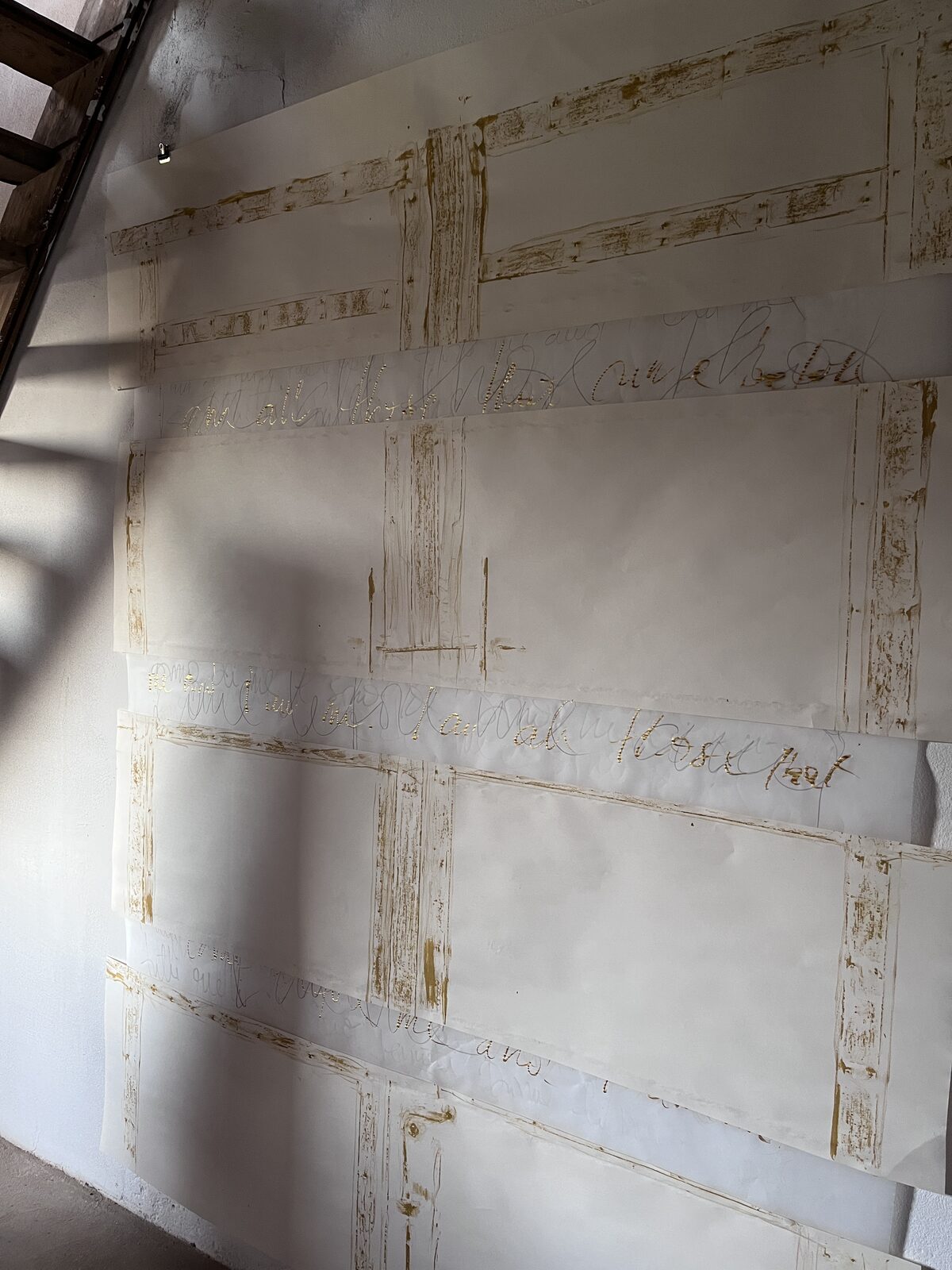 Il Portone in progress — large sheets of paper marked with gold and pencil cursive text, hung across the studio wall.